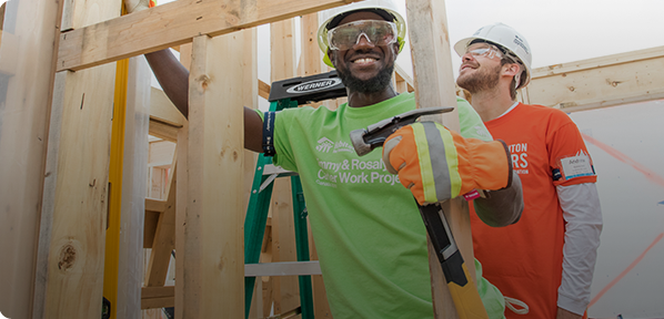 workers wearing habitat for humanity shirts building a house frame together 