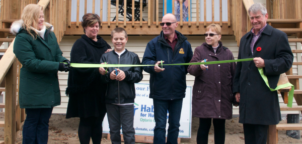 two family's cutting red ribbon to celebrate there new homes 