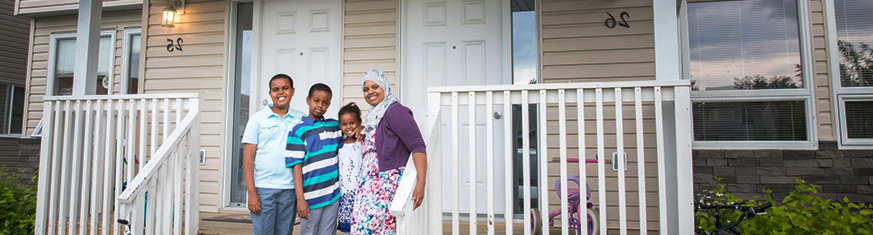 family of four smiling outside there home