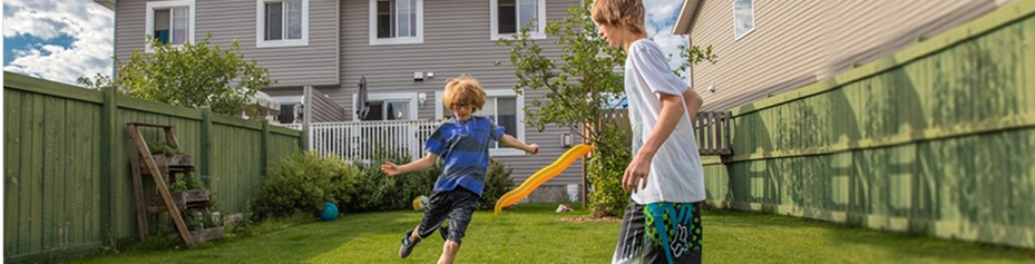 two kids playing soccer outside in their backyard 